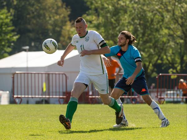 Football playing opponents racing for a football