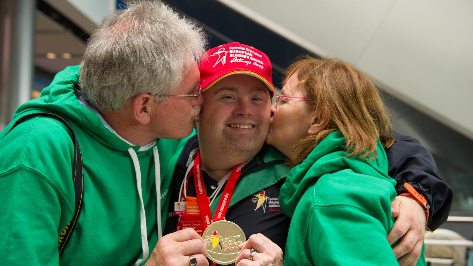 Picture of athlete being embraced by both parents