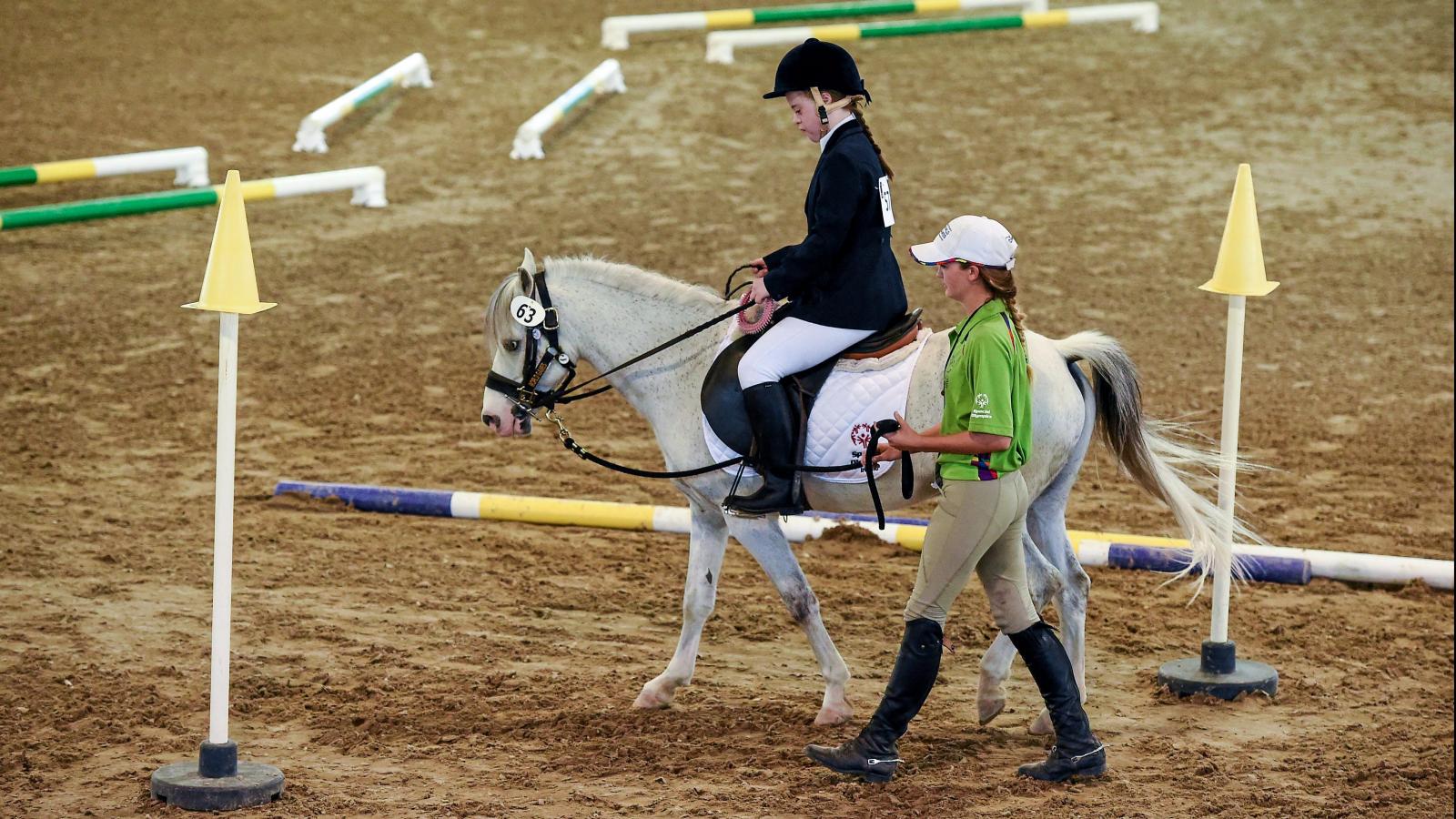 Girl riding horse around arena during competition